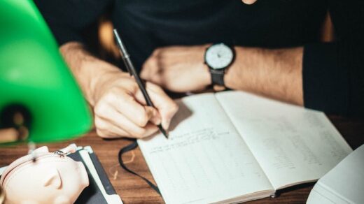 crop accountant taking notes at desk with scattered coins