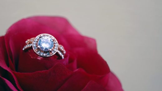 closeup photography of clear jeweled gold colored cluster ring on red rose