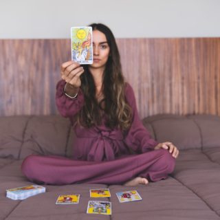 curly haired female holding a tarot card