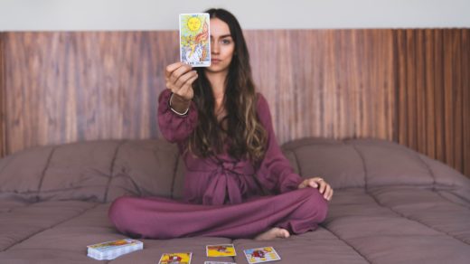 curly haired female holding a tarot card