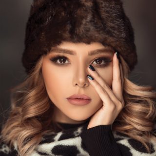 woman wearing brown fur beanies and white and balck top