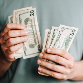 crop man counting dollar banknotes