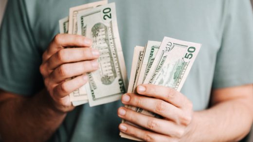 crop man counting dollar banknotes