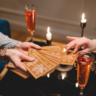 close up of woman picking a tarot card from a deck held by another woman