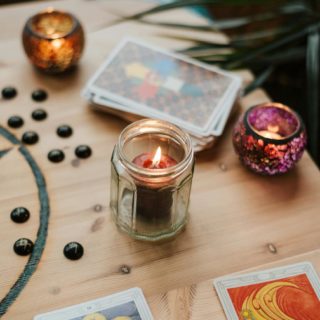 burning candles near tarot cards on table