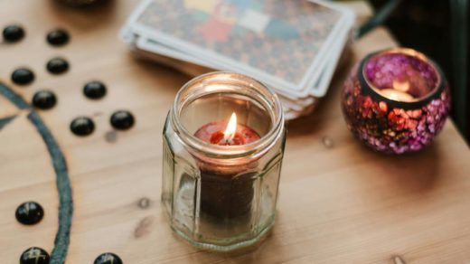 burning candles near tarot cards on table