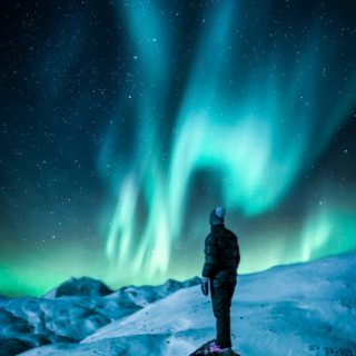 man standing on a rock near snow covered land