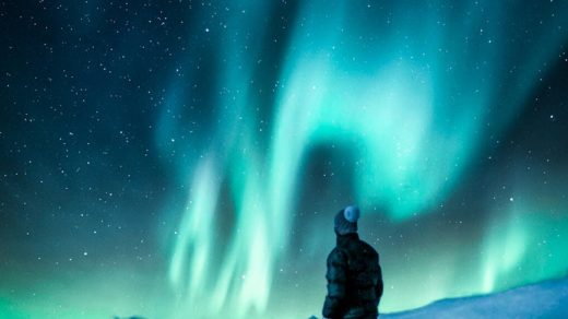 man standing on a rock near snow covered land