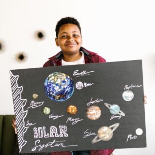 a kid holding a board while smiling at the camera