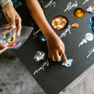 hand of a child putting stickers on a gray board