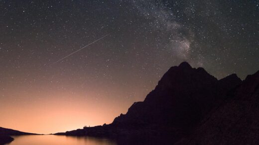 body of water near mountains under starry night