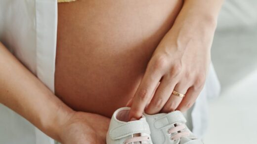 a pregnant woman holding baby shoes