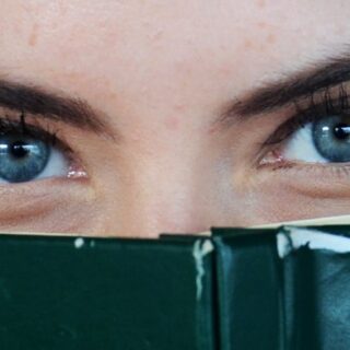 woman covering her face with green book