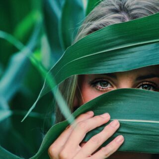 woman covering her face with corn leaves