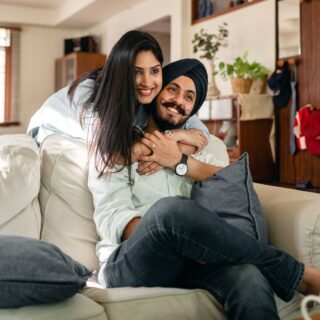 ethnic woman embracing husband on sofa in living room